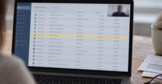 A laptop on a kitchen table showing a blurred list of transactions with one row highlighted